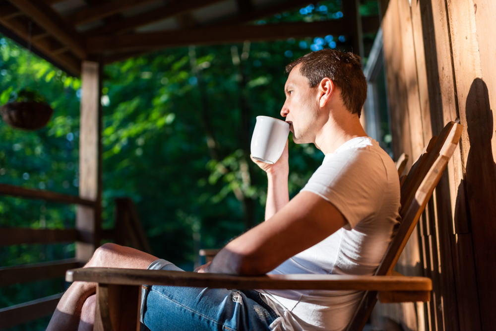 man drinking coffee on porch